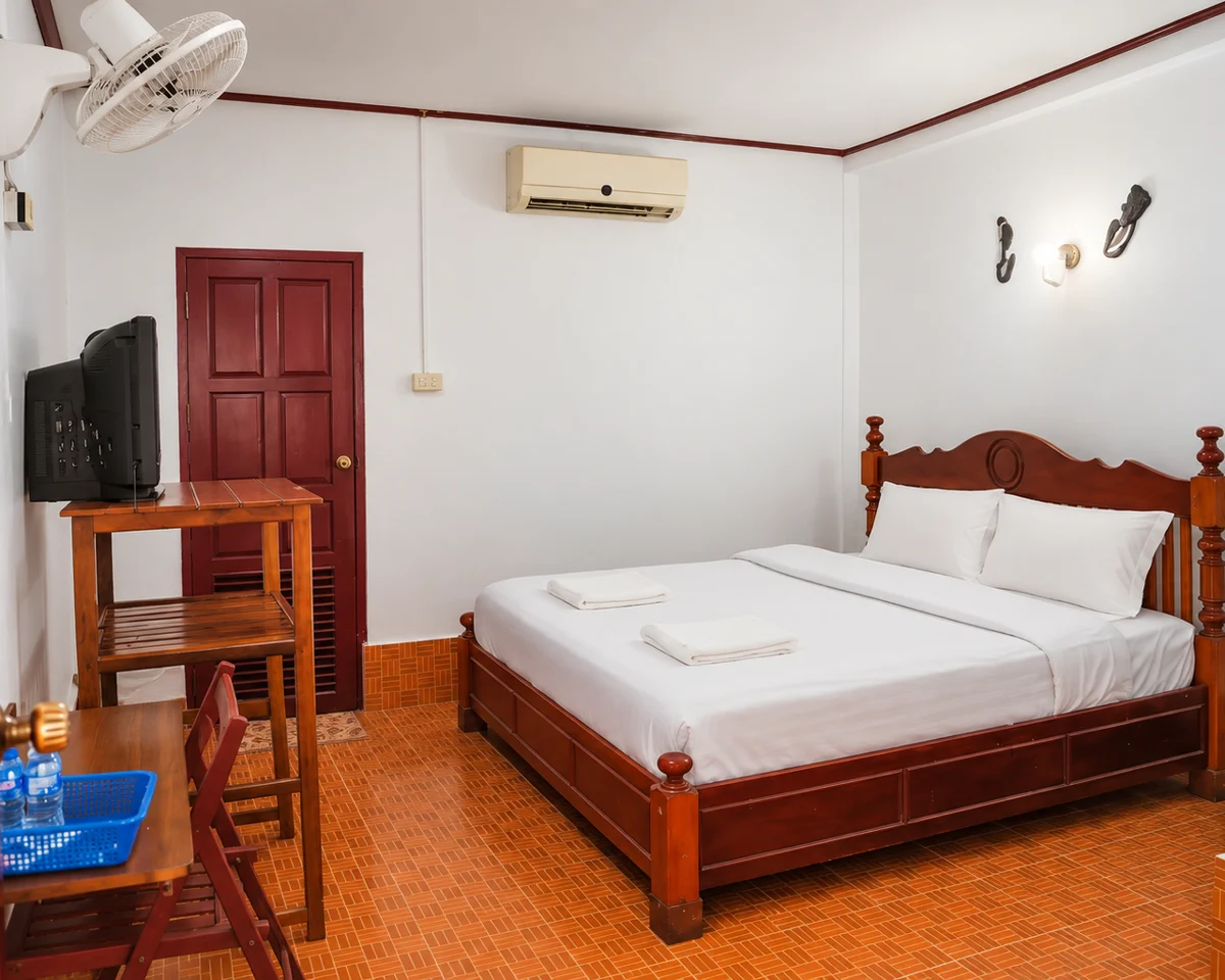 A guest room with warm wooden furniture and white bedding